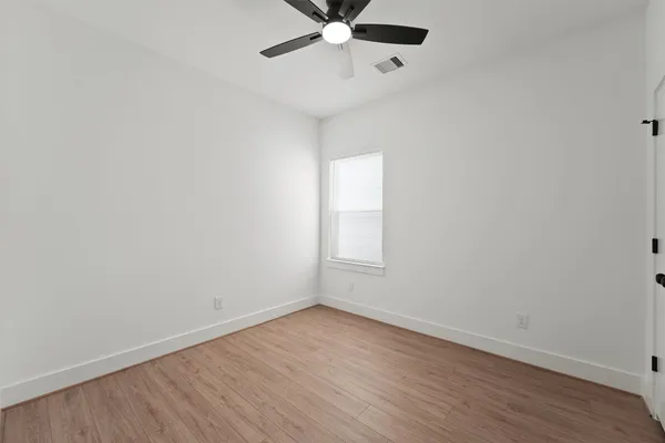 a view of an empty room with a window and wooden floor