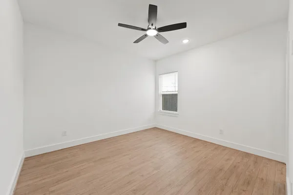 an empty room with a window and a fan