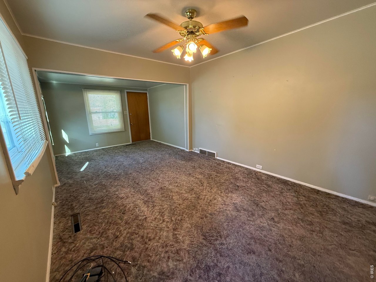 711 South 3rd Street Lamar, CO 81052 - Photo 4 of 30 an empty room with a chandelier fan and windows