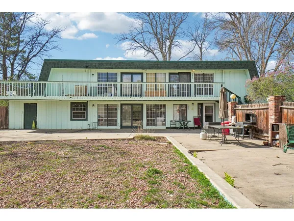 a front view of a building with a garden and trees