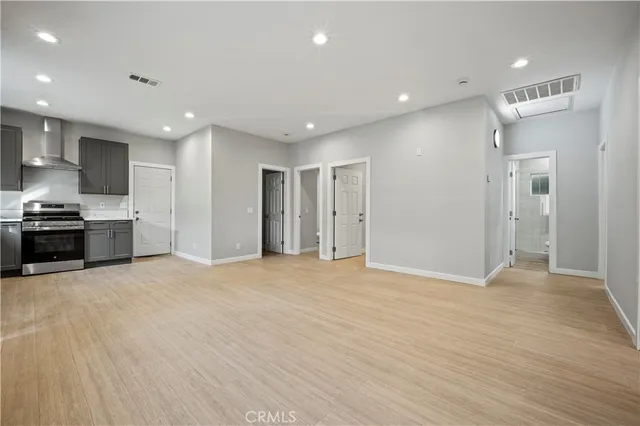 a view of an empty room with kitchen and window