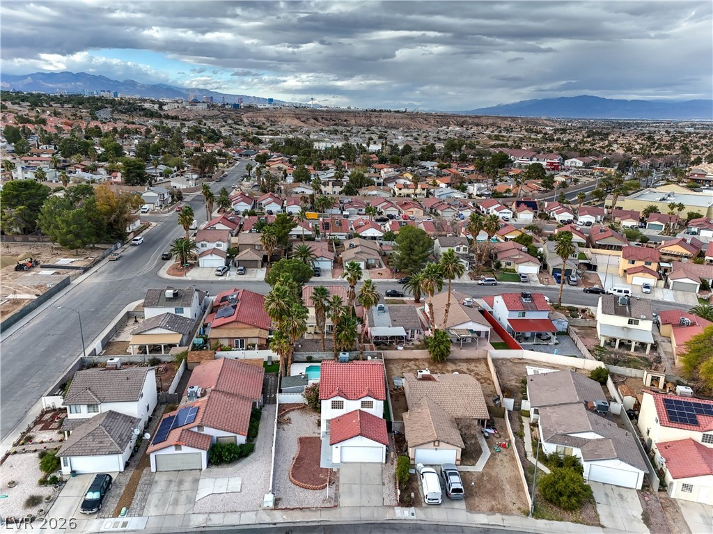 581 Carleton Drive Henderson, NV 89014 - Photo 36 of 37 An aerial perspective reveals a vibrant neighborhood nestled against distant mountains under a dramatic sky.