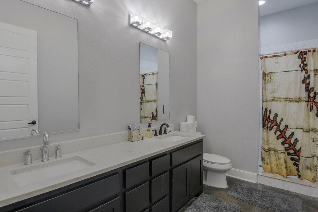 239 North Armstrong Road Venus, TX 76084 - Photo 25 of 39 Bathroom featuring a double vanity with light-toned countertops, dark cabinetry, and dual sinks