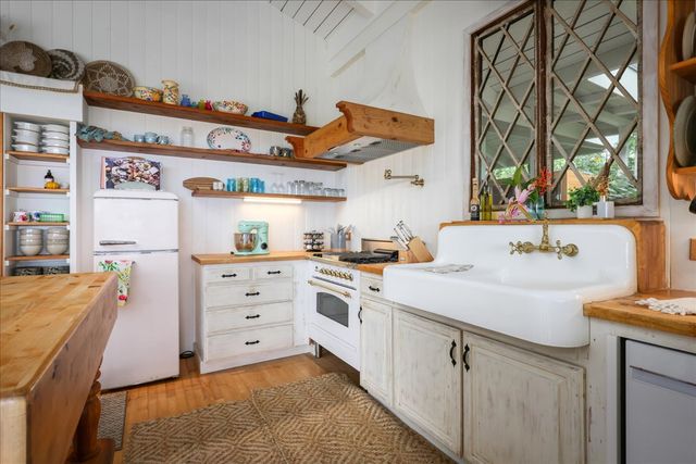 a kitchen with stainless steel appliances kitchen island wooden cabinets a stove a sink and a large window