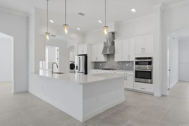 a large white kitchen with kitchen island a sink a center island stainless steel appliances and a fireplace
