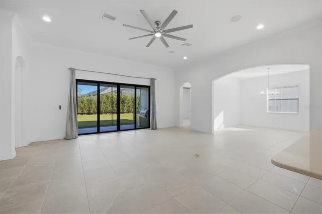 an empty room with chandelier fan and windows