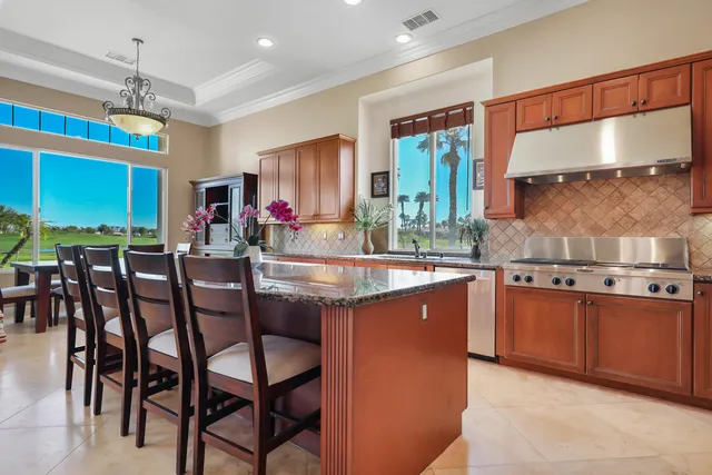a kitchen with stainless steel appliances granite countertop wooden cabinets a dining table and chairs