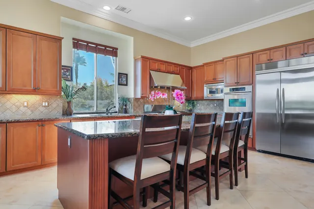 a kitchen with stainless steel appliances granite countertop a dining table chairs and granite counter tops