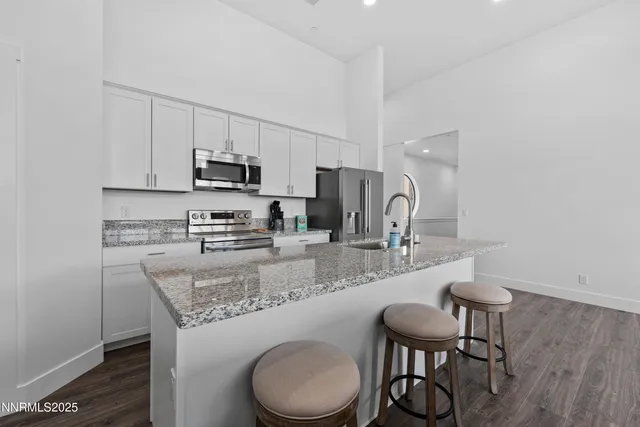 a kitchen with stainless steel appliances granite countertop a kitchen island a white cabinets a sink and a stove