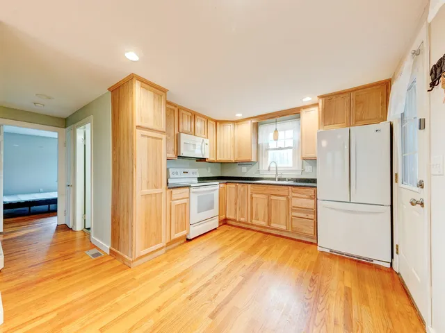 a kitchen with granite countertop wooden floors white cabinets and stainless steel appliances