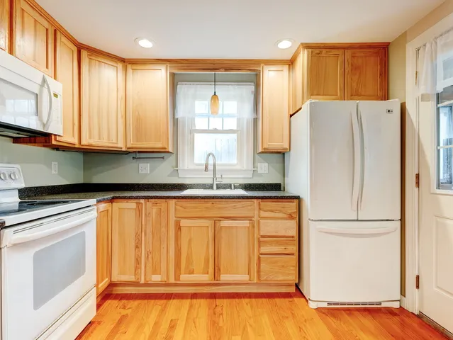 a view of a hallway with wooden floor and a bathroom
