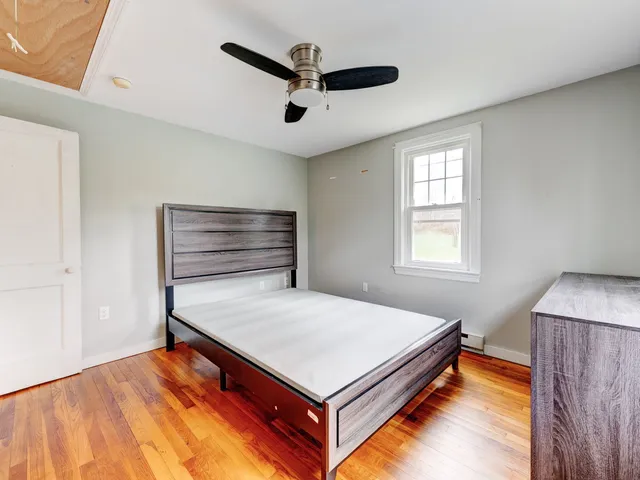 a view of a bedroom with wooden floor and window