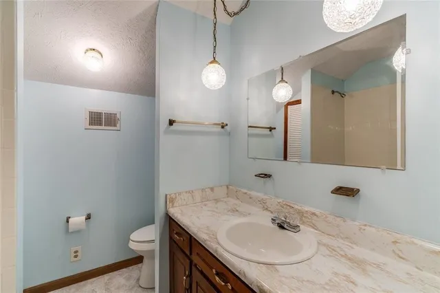 a bathroom with a granite countertop sink a toilet and a mirror