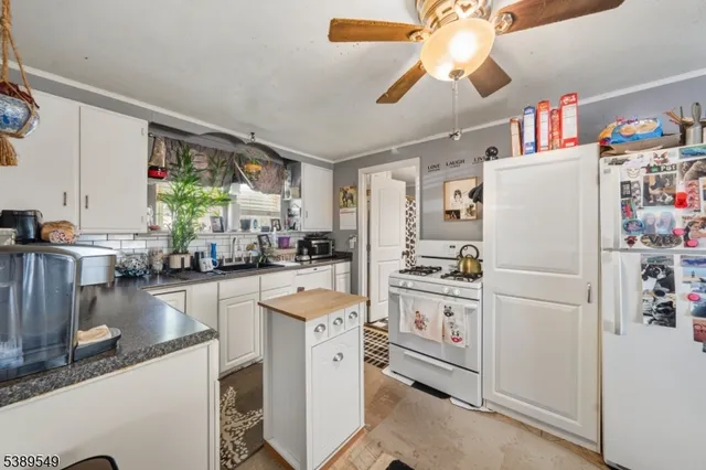 a kitchen with a refrigerator a stove cabinets dining table and chairs