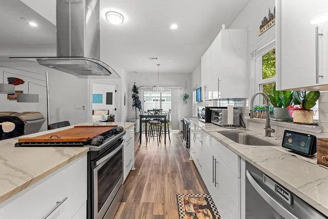 a kitchen with stainless steel appliances a sink a stove and white cabinets next to a window