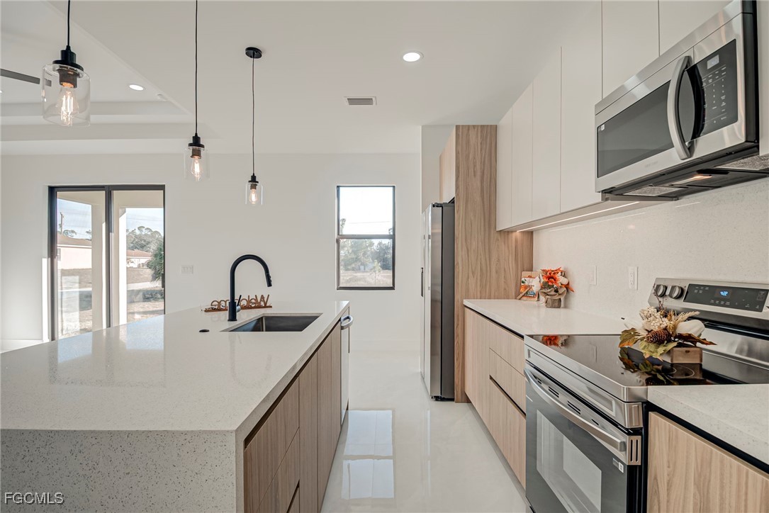 3601 28th Street Southwest Lehigh Acres, FL 33976 - Photo 11 of 35 a kitchen with stainless steel appliances a sink dishwasher a stove a microwave oven with cabinets