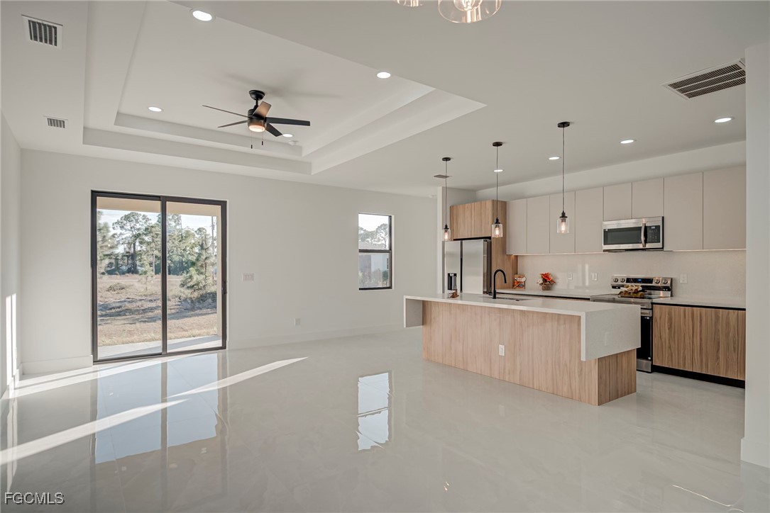 3601 28th Street Southwest Lehigh Acres, FL 33976 - Photo 12 of 35 a large kitchen with stainless steel appliances a large counter top a stove a sink a window and white cabinets