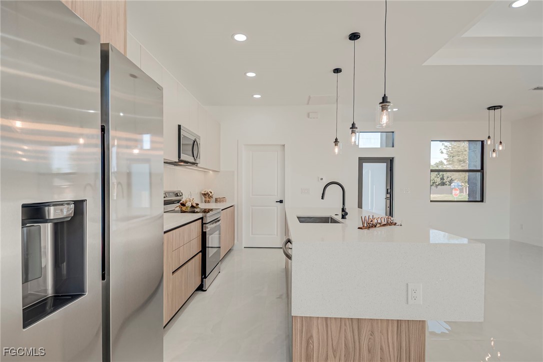 3601 28th Street Southwest Lehigh Acres, FL 33976 - Photo 10 of 35 a kitchen with stainless steel appliances a refrigerator sink and white cabinets