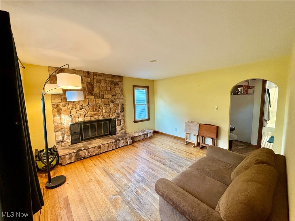 Living room with hardwood / wood-style flooring and a stone fireplace