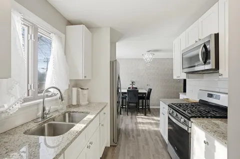 a kitchen with granite countertop a sink stove and cabinets