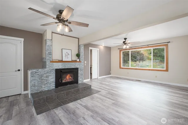 a view of an empty room with wooden floor fireplace and a window