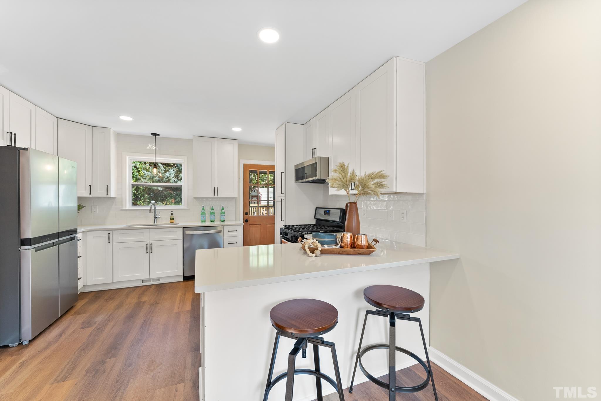 401 Plainview Avenue Raleigh, NC 27604 - Photo 10 of 28 a kitchen with stainless steel appliances a dining table chairs refrigerator and sink