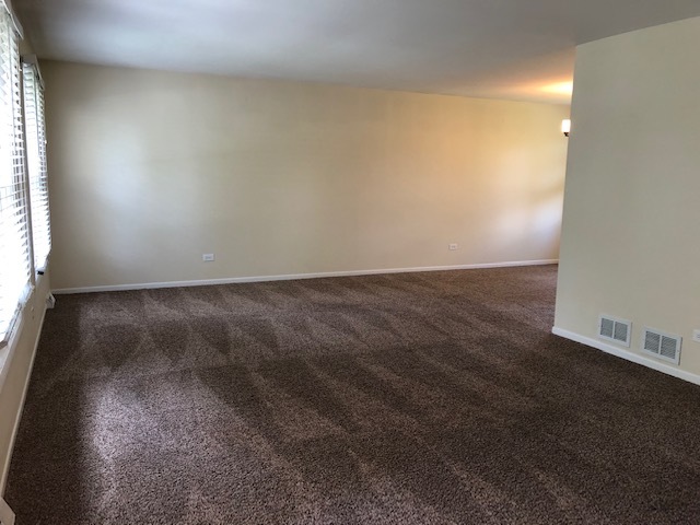 624 Quail Run Road Matteson, IL 60443 - Photo 7 of 30 an empty room with wooden floor and windows with curtains