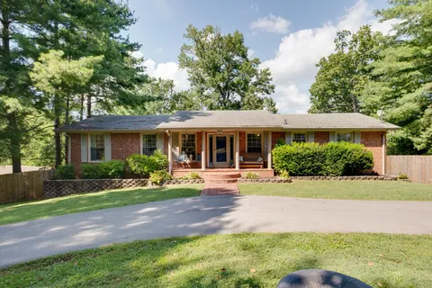 a view of a house with a yard and large tree