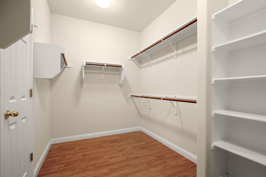 10105 Wind Cave Trail Austin, TX 78747 - Photo 13 of 23 Walk-in closet featuring wood-finish flooring, white baseboards, multiple white shelving units, and integrated hanging rods