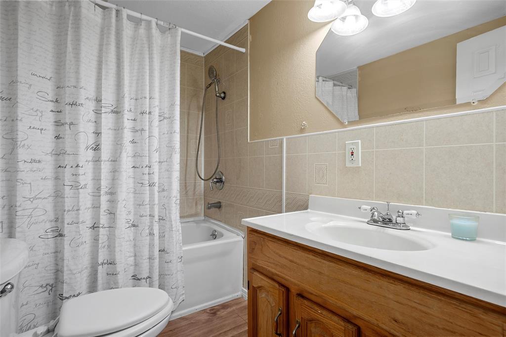 4704 Williams Road Bellmead, TX 76705 - Photo 21 of 32 Bathroom featuring a white bathtub, ceramic tile surround, and an integrated shower head with a handheld sprayer