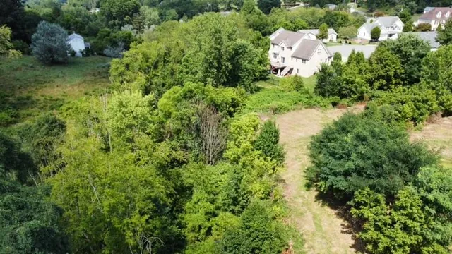 an aerial view of residential house with outdoor space and trees all around