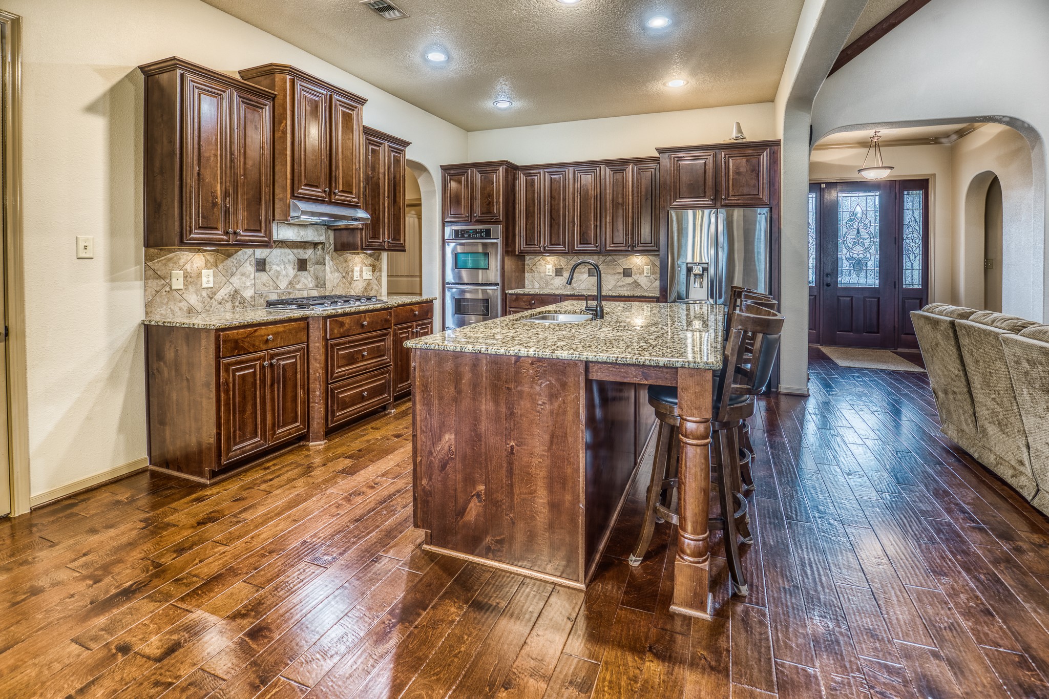 677 Grubbs Road Sealy, TX 77474 - Photo 8 of 40 a kitchen with kitchen island granite countertop wooden floors wooden cabinets a center island and stainless steel appliances