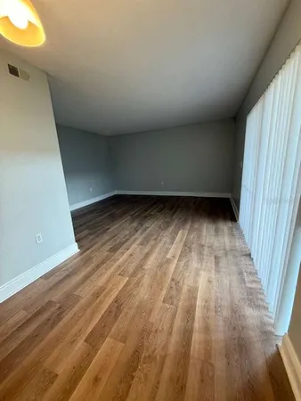 a view of an empty room with wooden floor and a window