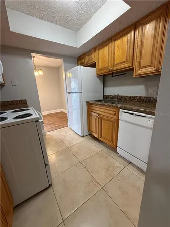 a kitchen with granite countertop a refrigerator and a stove top oven