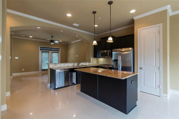 a large kitchen with a large counter top a sink and stainless steel appliances