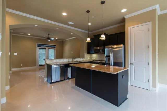 a large kitchen with a large counter top a sink and stainless steel appliances