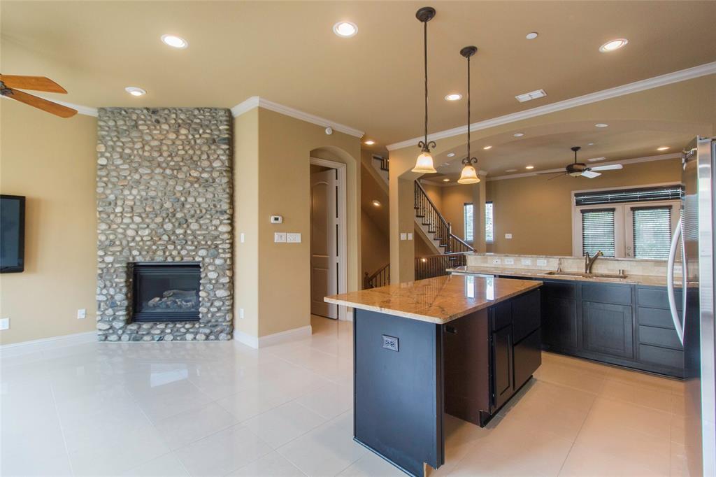7416 Bishop Road Plano, TX 75024 - Photo 23 of 40 a kitchen with kitchen island a stove a counter top space a sink and a fireplace