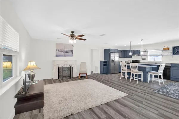 a living room with couches and kitchen view with wooden floor