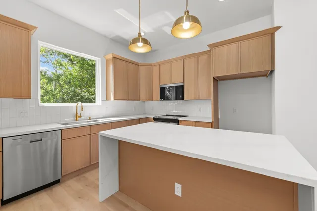 a kitchen with a sink dishwasher a stove and a refrigerator with wooden floor