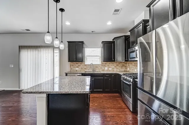 a kitchen with stainless steel appliances granite countertop a refrigerator a sink and a stove