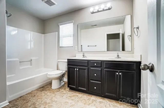 a bathroom with a granite countertop toilet sink and mirror