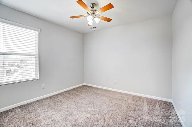 an empty room with a window and a fan