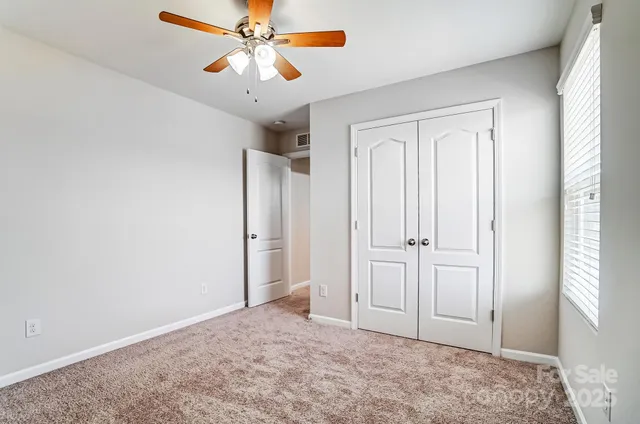 a view of empty room with window and ceiling fan