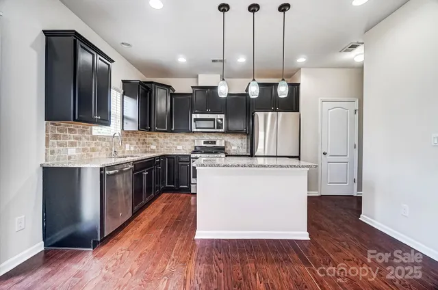 a kitchen with kitchen island a counter top space a sink appliances and cabinets