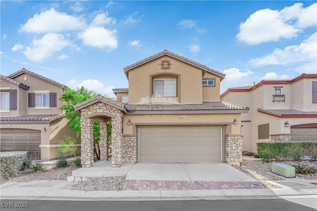 Mediterranean / spanish house featuring stone siding, stucco siding, an attached garage, driveway, and a tiled roof