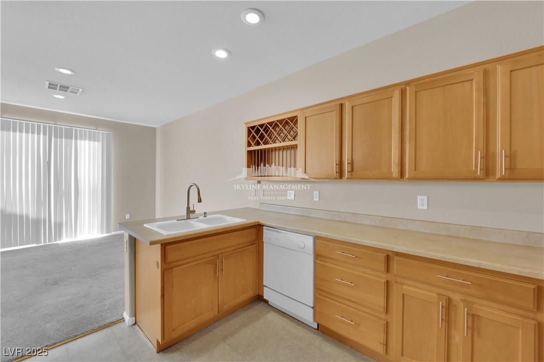 8661 Rowland Bluff Avenue Las Vegas, NV 89178 - Photo 13 of 37 Kitchen with light countertops, a peninsula, recessed lighting, dishwasher, and light colored carpet