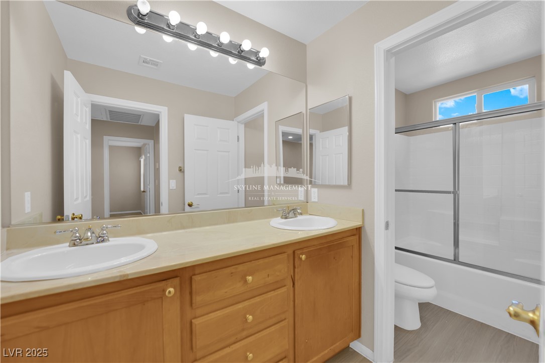 8661 Rowland Bluff Avenue Las Vegas, NV 89178 - Photo 18 of 37 Full bath featuring double vanity, bath / shower combo with glass door, and light wood finished floors