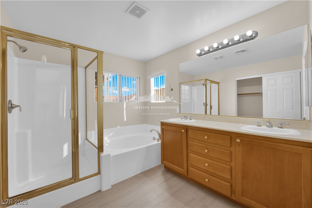 8661 Rowland Bluff Avenue Las Vegas, NV 89178 - Photo 28 of 37 Bathroom featuring a garden tub, double vanity, a shower stall, and a walk in closet