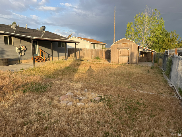 874 770 South Tooele, UT 84074 - Photo 19 of 19 Expansive rear yard featuring a utility shed and a covered patio area