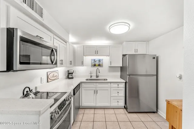 a kitchen with a sink a refrigerator and a stove top oven with white cabinets
